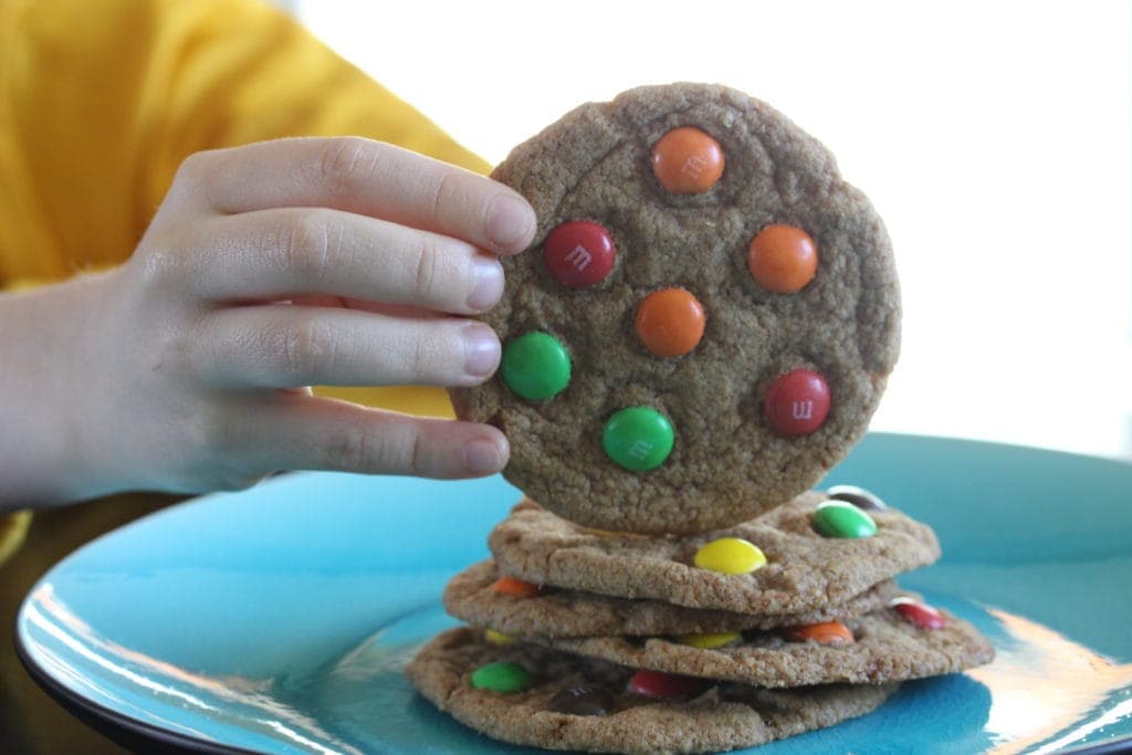 Child taking a soft M&M cookie. #glutenfree #vegan #dairyfree #recipe #cookie #glutenfreecookie #fairyflour