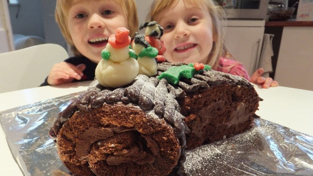 Happy children with their gluten free yule log fully decorated in front