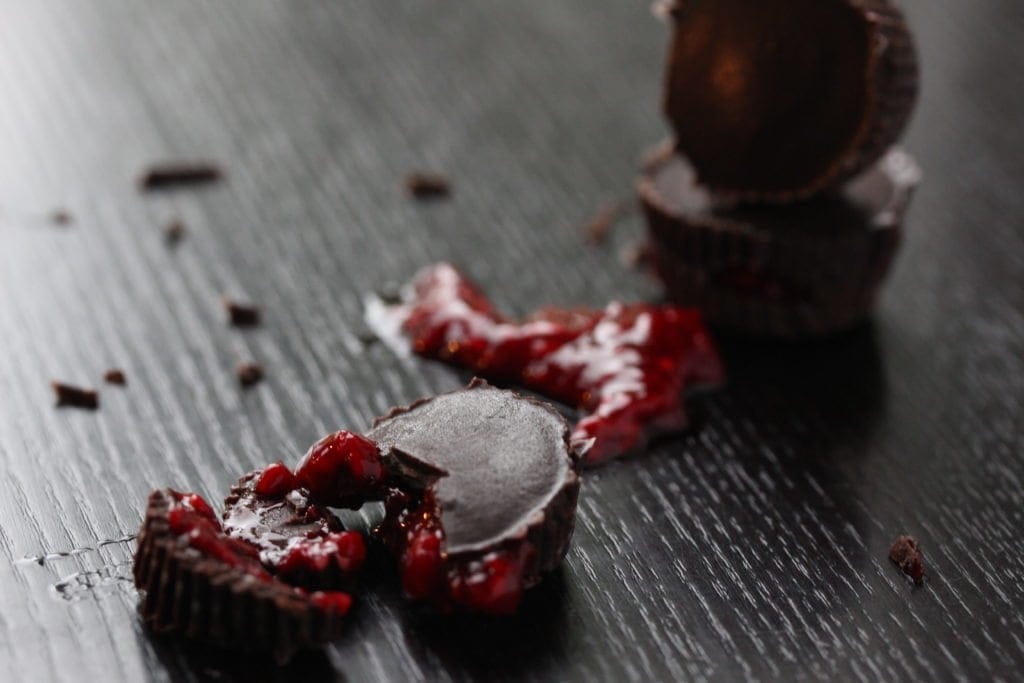 Raspberry sauce filled homemade chocolates. This simple recipe is perfect for halloween. Bite into the homemade refined sugar-free dark chocolate to find 'blood' inside!