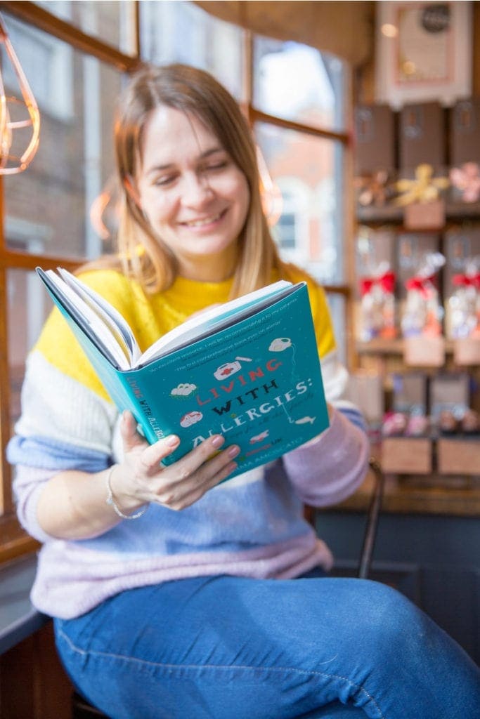 Emma Amoscato with a copy of the Living with Allergies book