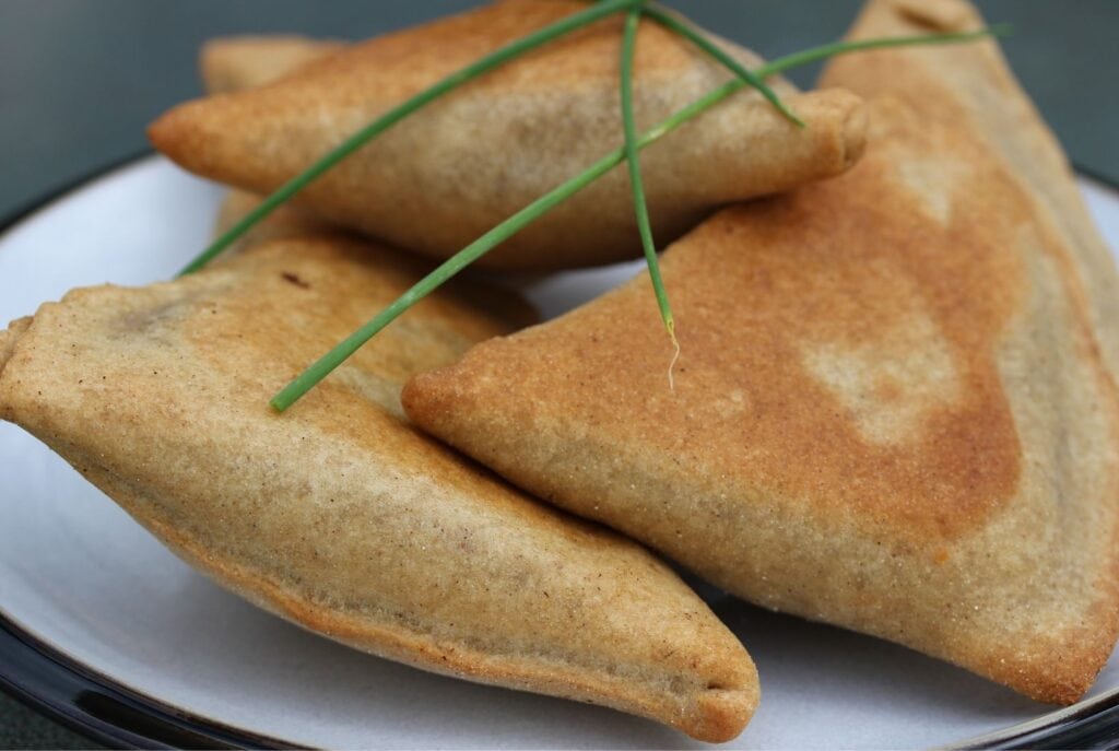 Gluten free samosas, side on view with a scattering of chives on the top.