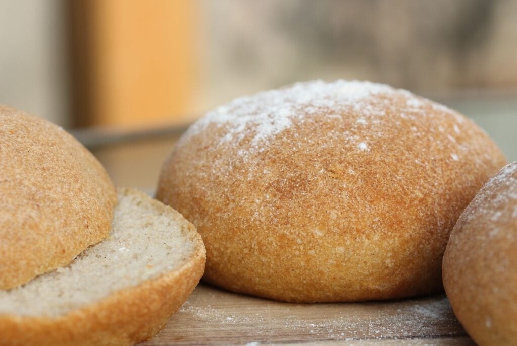 Gluten free burger bun side on view with a cut roll in the foreground