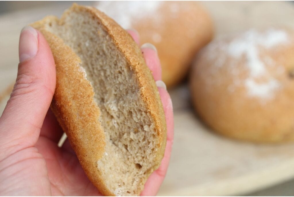 Half a gluten free burger bun folded in half to show how soft and pliable the rolls are.