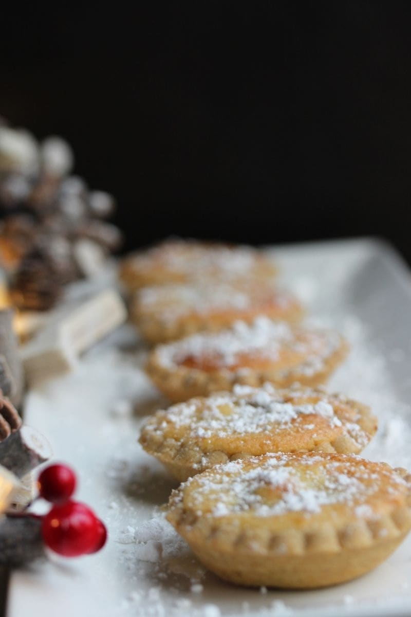 Close up of frangipane topped mince pies on a white plate